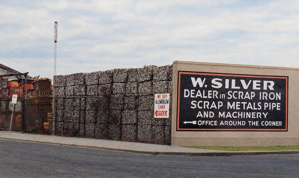 Restored historical photograph of the W. Silver sign beside stacked scrap-metal bales